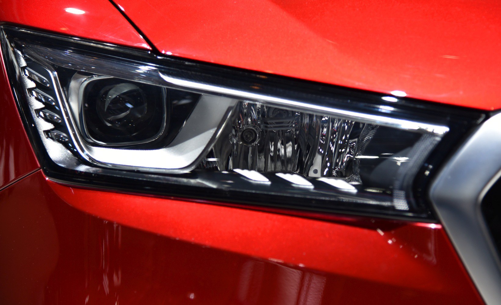 Close-up of a detailed car headlight with projector lens and LED accents