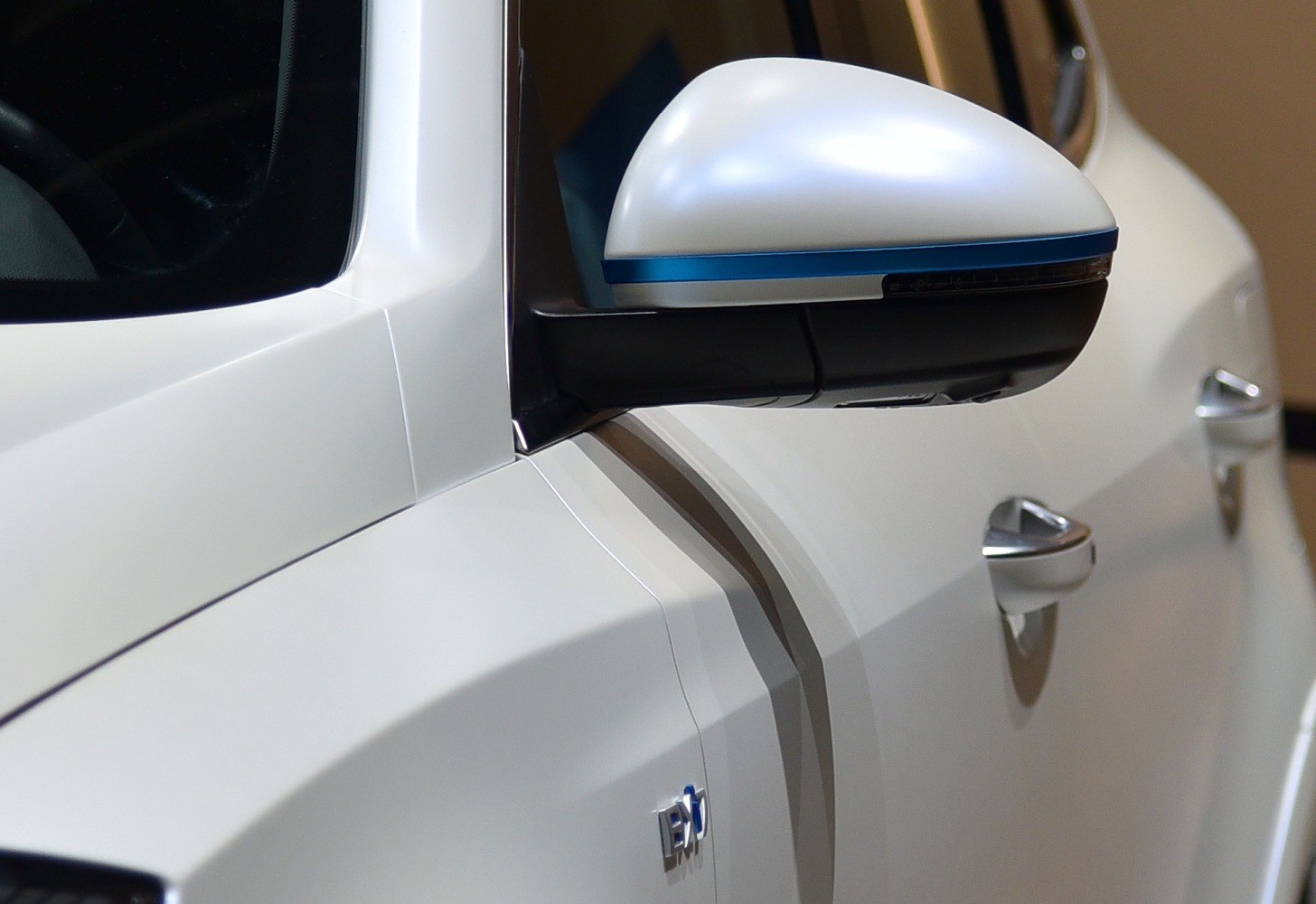 Close-up of futuristic side mirror and door handles on white car exterior