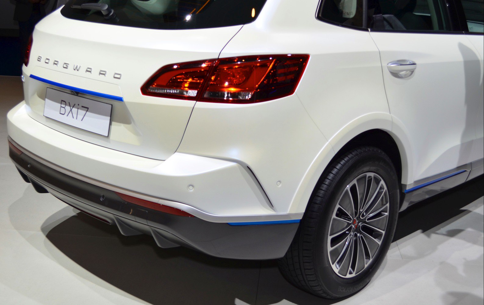 Rear view of sleek taillights and alloy wheel of a white SUV.