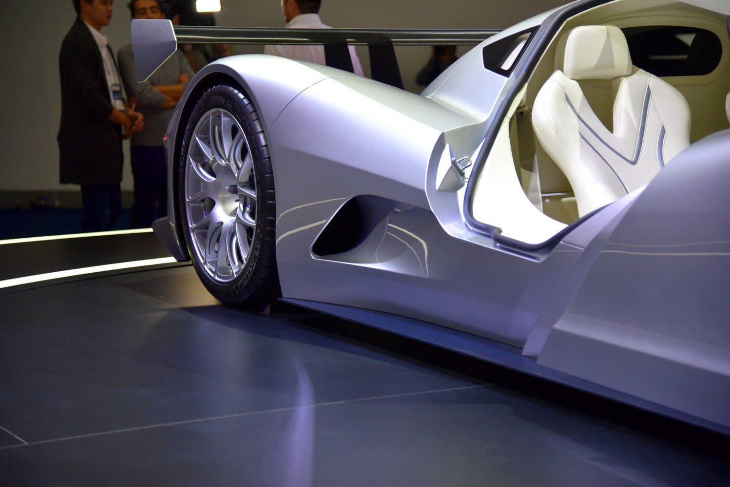 Silver car side with open door showing alloy wheel and white seat