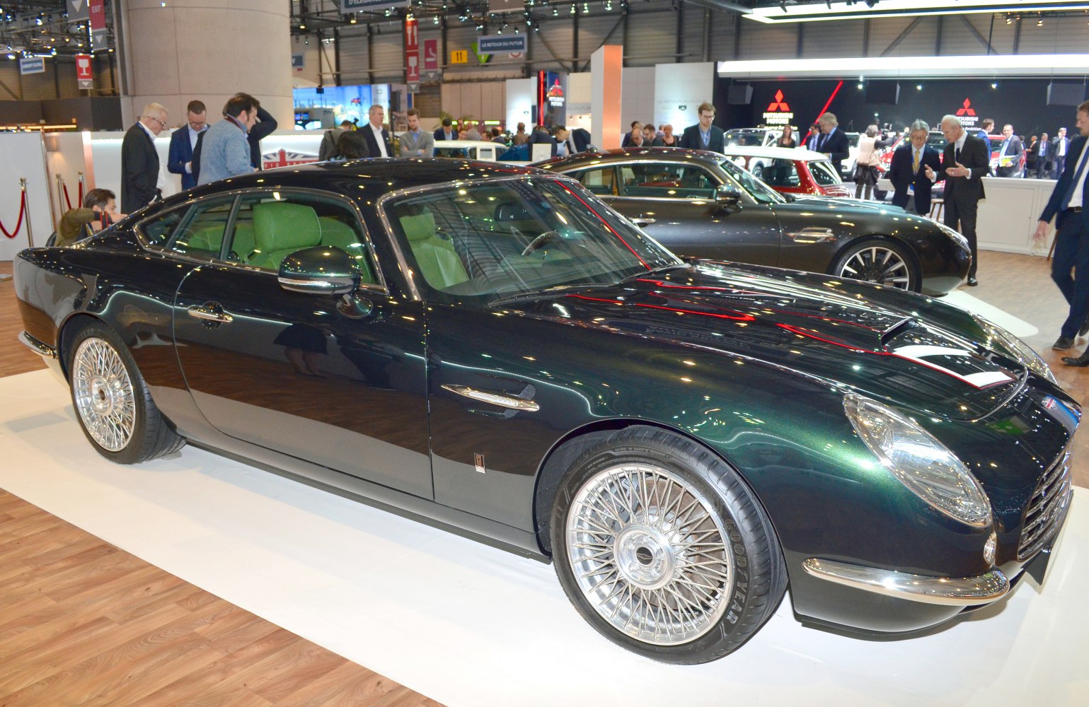 Classic luxury coupe with wire-spoke wheels and elegant body design at an auto show