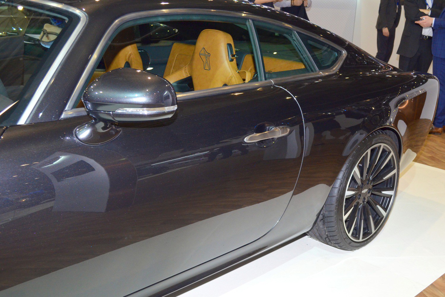 Side profile with mirror, door, wheel, and tan leather interior