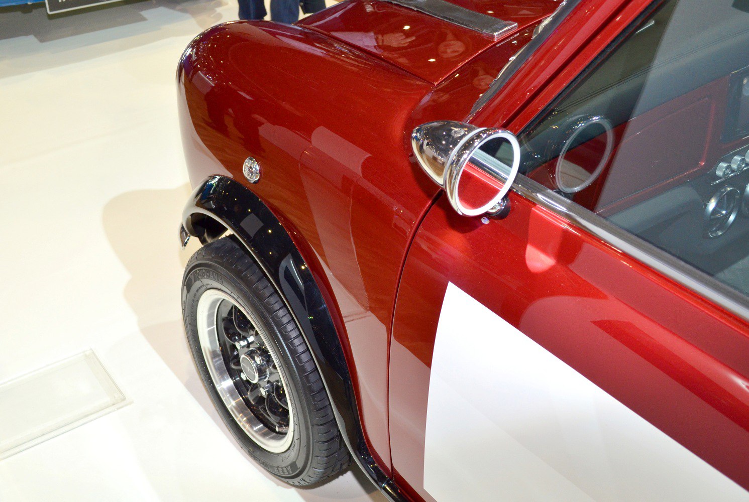 Close-up of wheel arch with black fender flare and chrome side mirror.