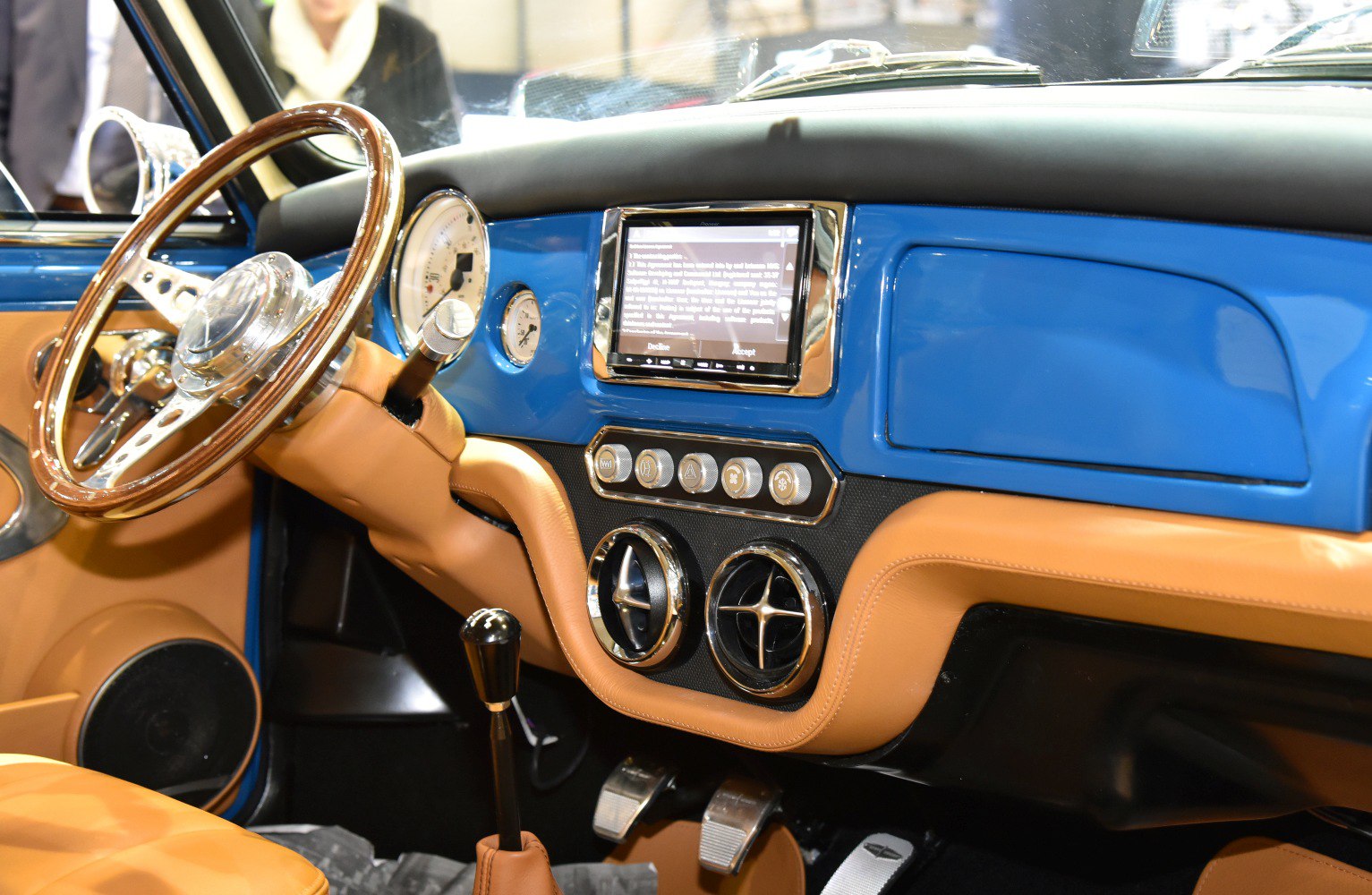 Vintage wooden steering wheel with modern dashboard featuring touchscreen and classic gauges