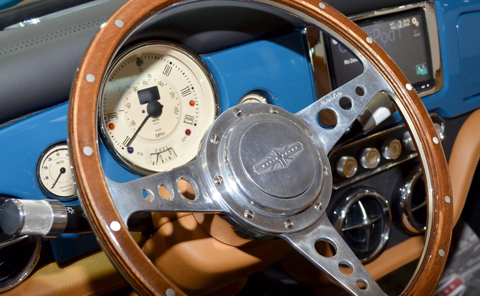 Classic wood steering wheel and vintage-style dashboard gauges in blue interior