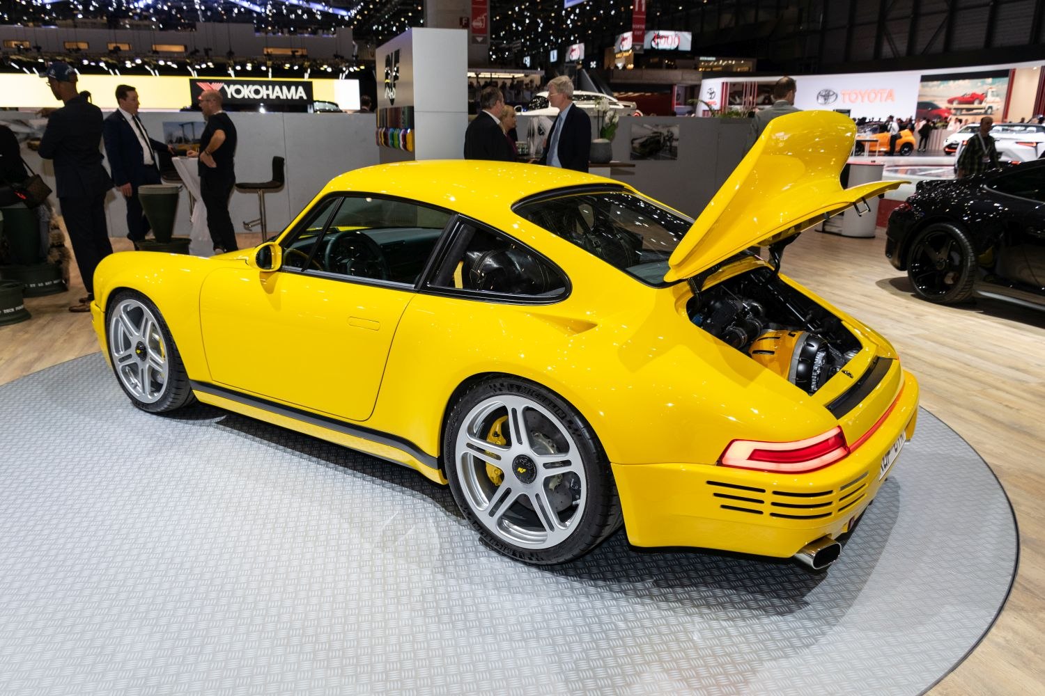 Yellow sports coupe with rear engine bay open and silver alloy wheels