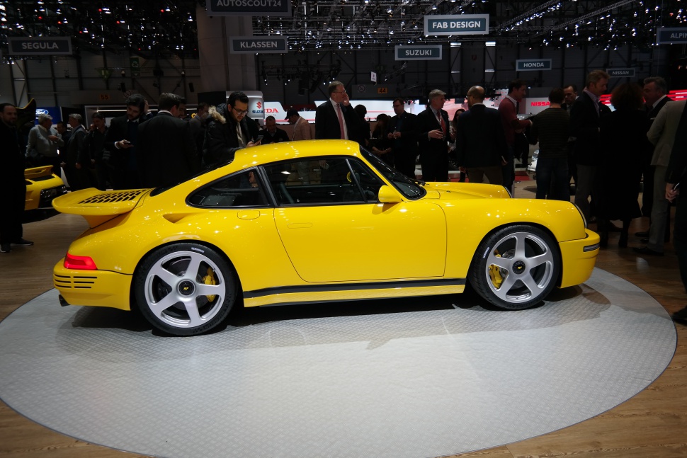 Yellow sports car with wide rear wing and five-spoke silver rims