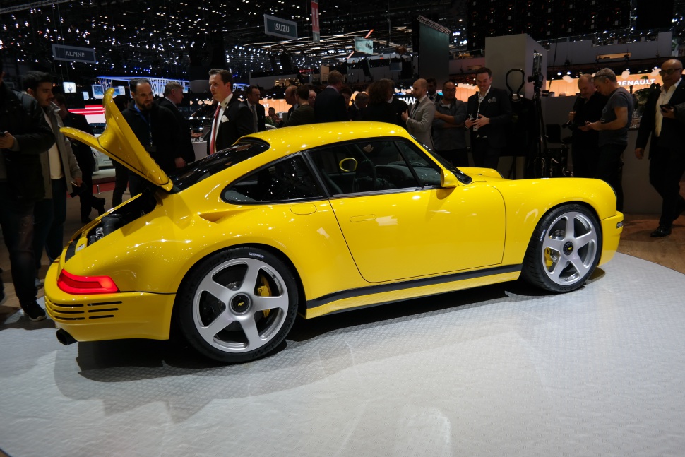 Side view of a yellow sports coupe with rear engine compartment open and silver wheels