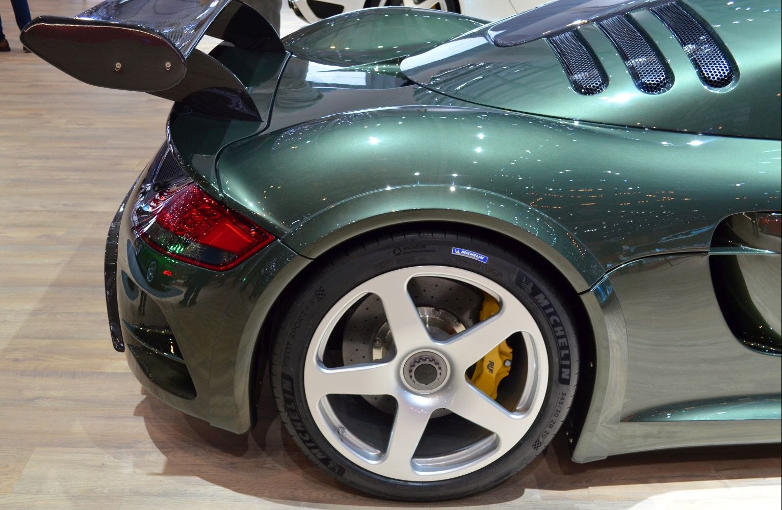 Rear wheel with yellow brake caliper and carbon fiber spoiler