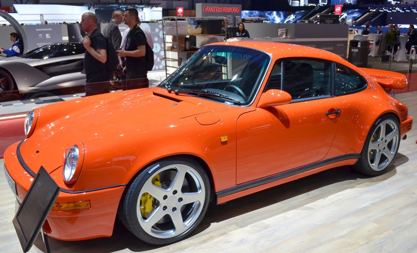 Orange sports coupe, rounded headlights, wide body, five-spoke wheels