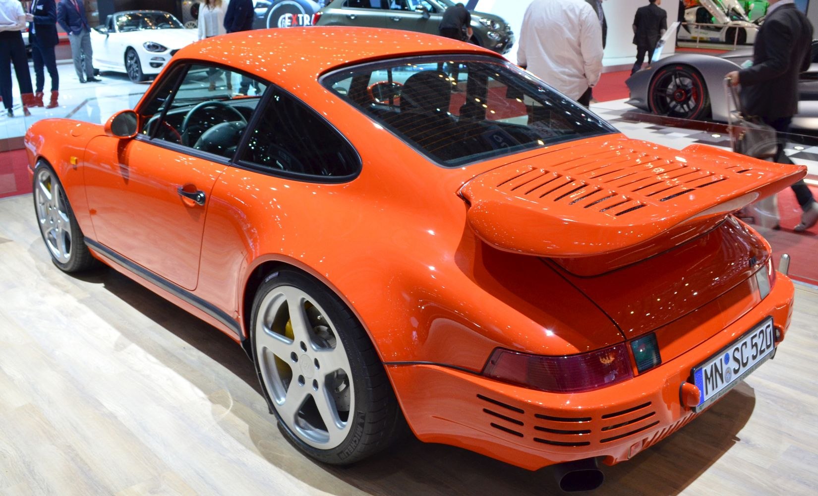 Orange sports car rear with large wing and wide fenders
