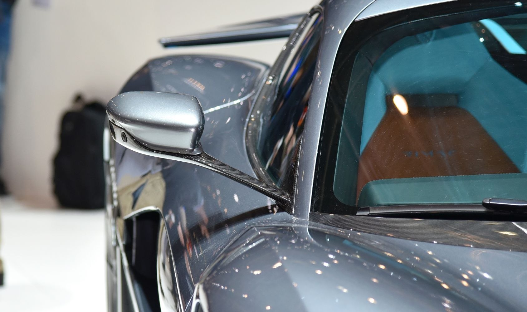 Close-up of side mirror with carbon fiber mount on sleek car body.