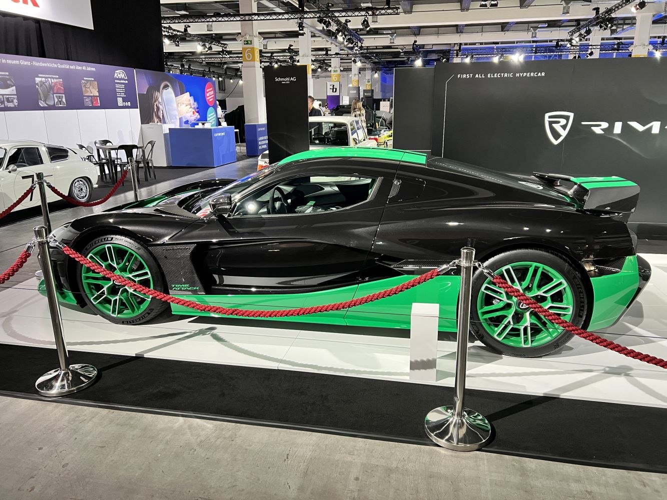 Side profile of a sleek black and green electric hypercar with aerodynamic design and green wheels.