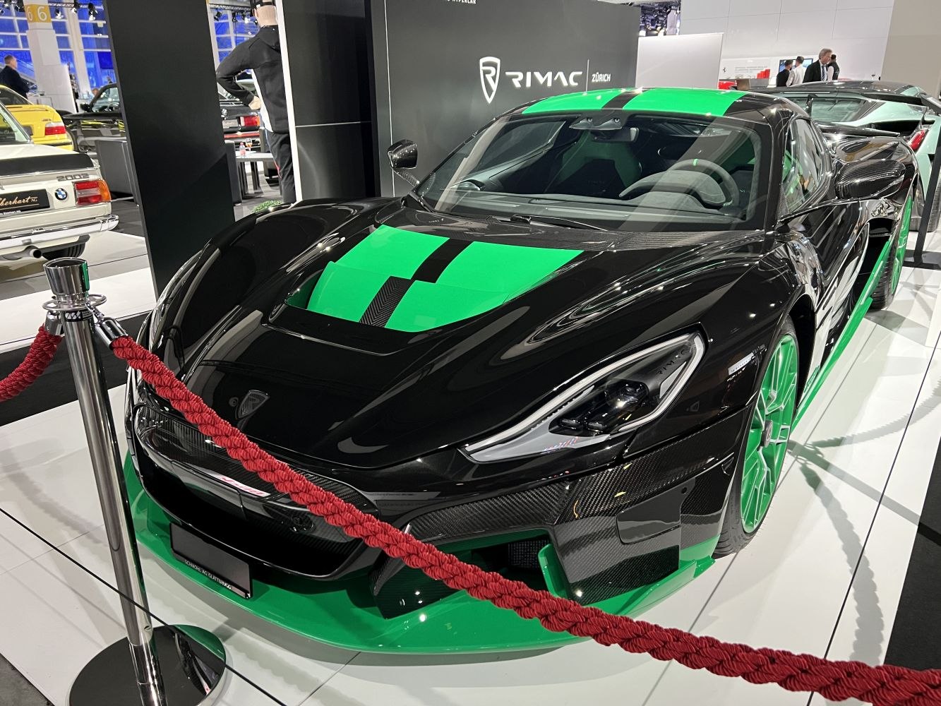 Black and green electric hypercar with racing stripes and aerodynamic front.