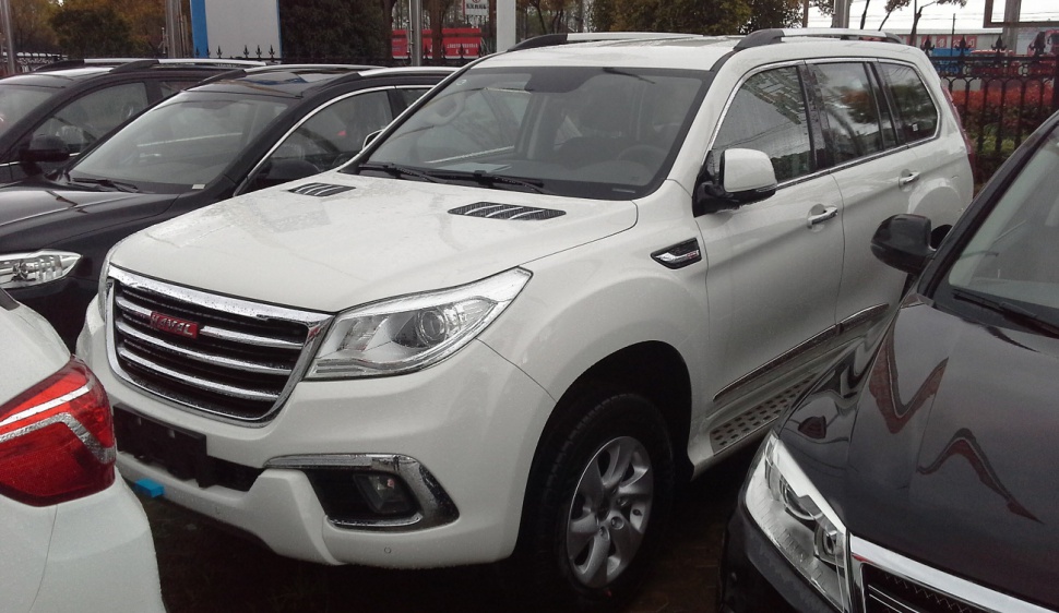 White SUV with hood vents and side step in crowded parking