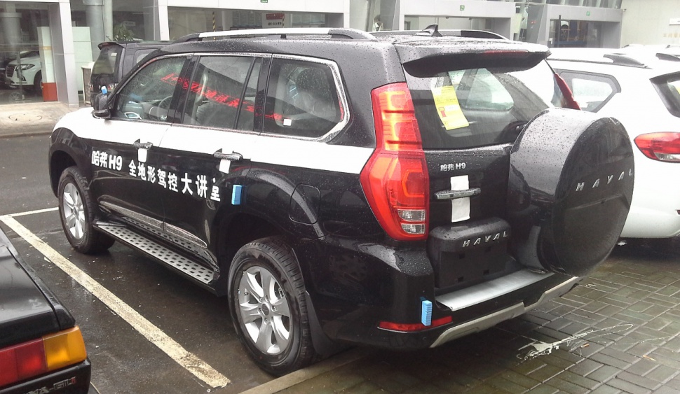 Black SUV rear with spare tire cover and side profile showing alloy wheels and side step