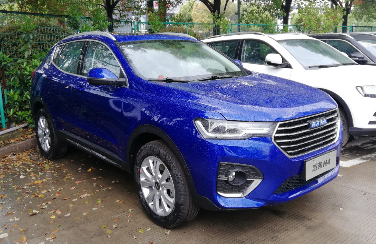 Blue compact SUV front side with LED headlights on wet ground