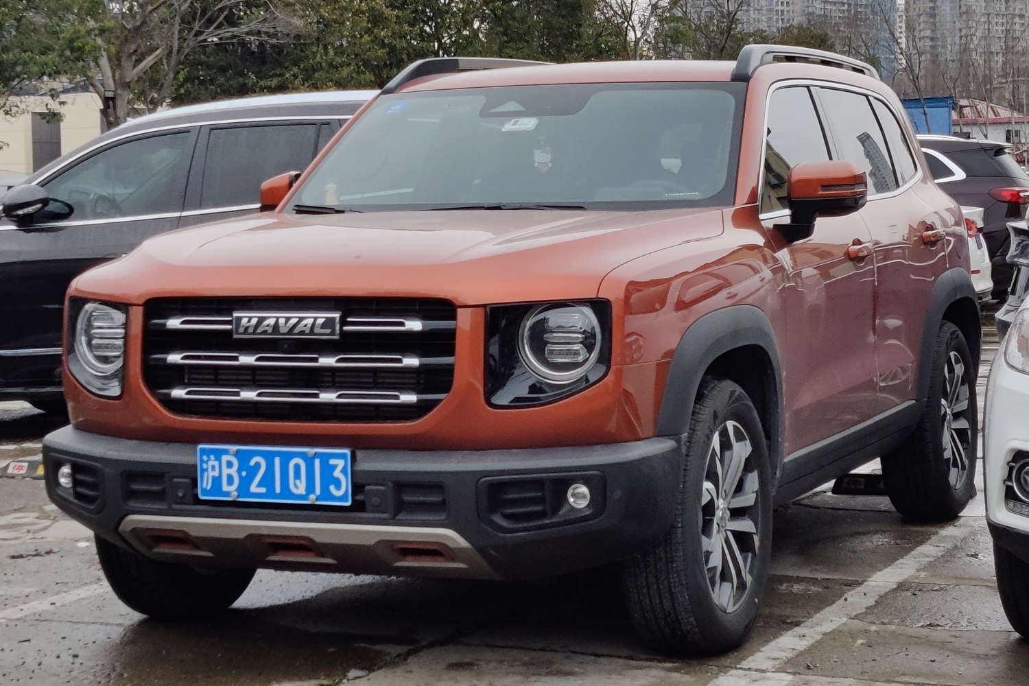 Orange SUV with bold grille, round LED headlights, roof rails, and rugged cladding