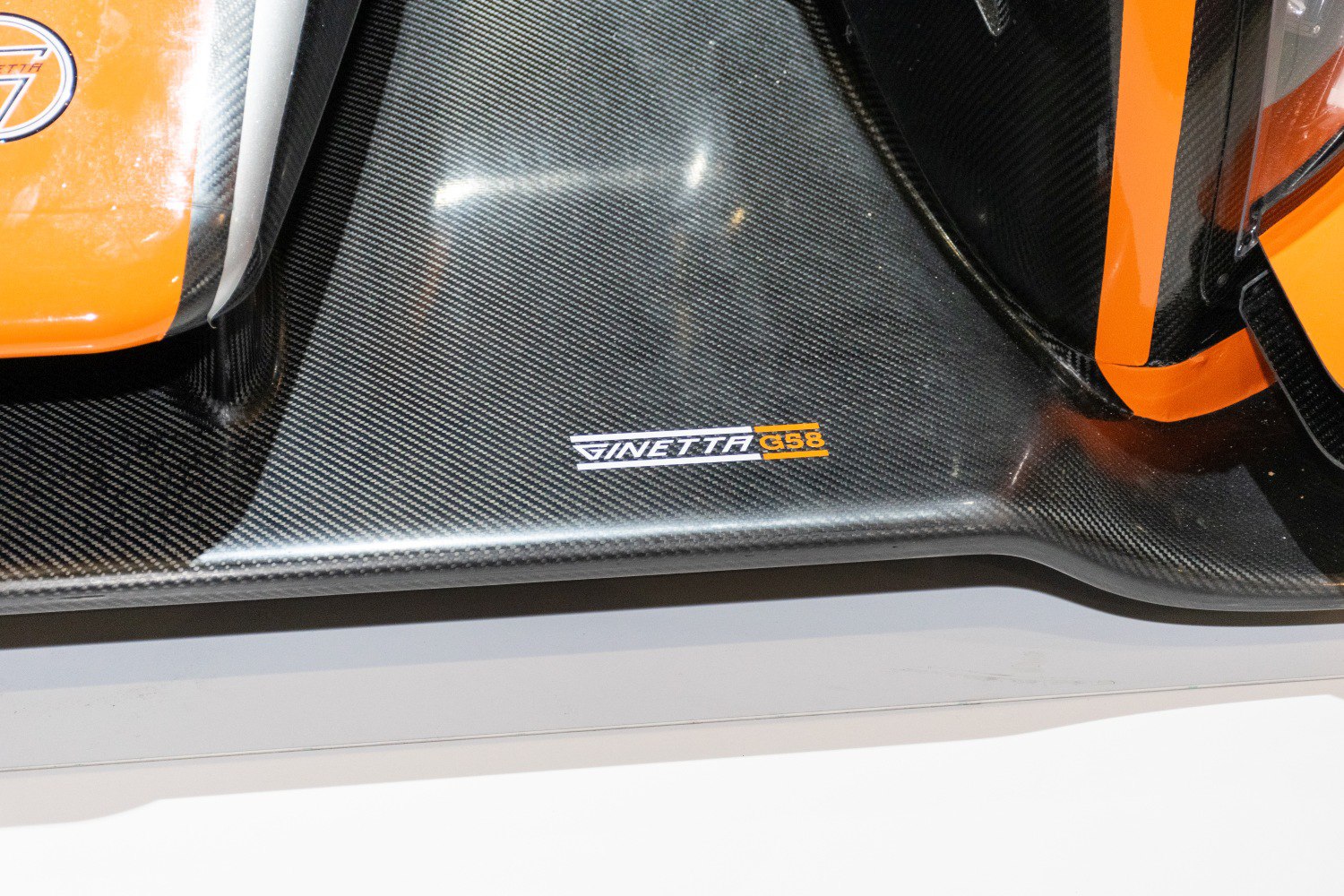 Close-up of carbon fiber side skirt with G58 logo and orange accents