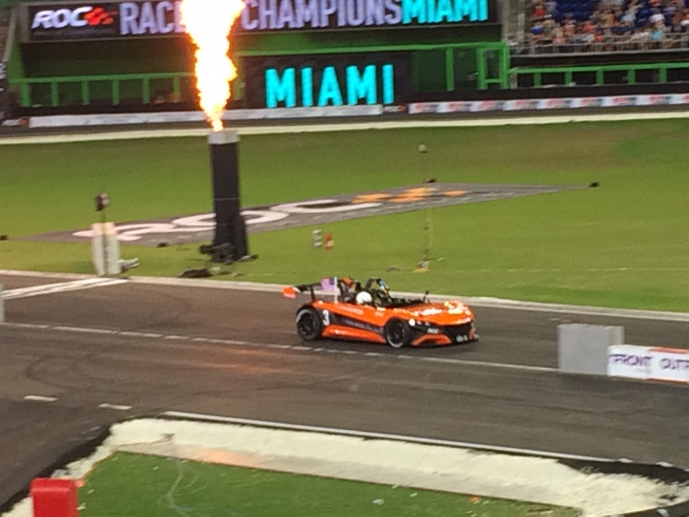 Orange open-cockpit racecar on track with flame display.