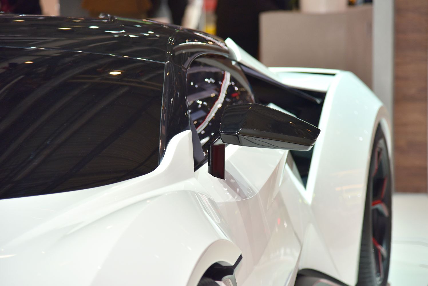 Close-up of side mirror and aerodynamic body lines on white sports car.