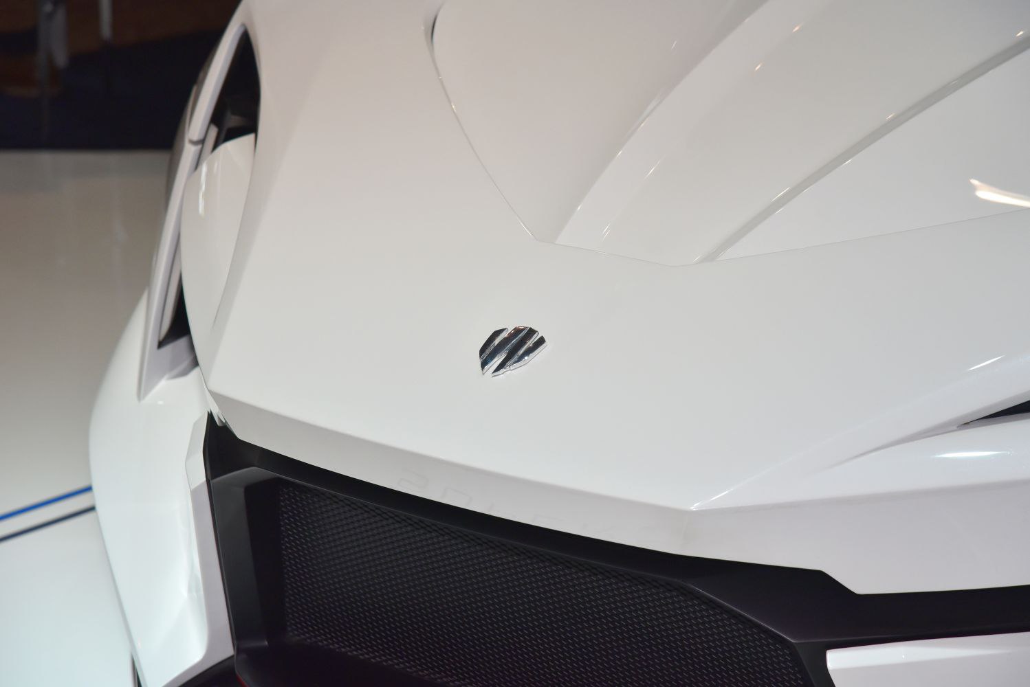 Close-up of a sharp front grille and emblem on white car body