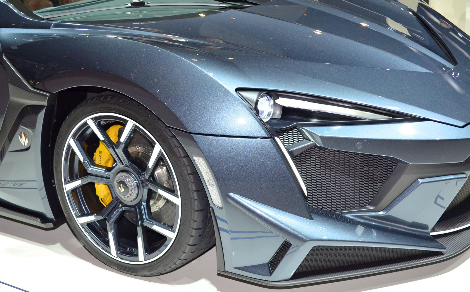 Close-up of front wheel with alloy rim and headlight with aerodynamic design