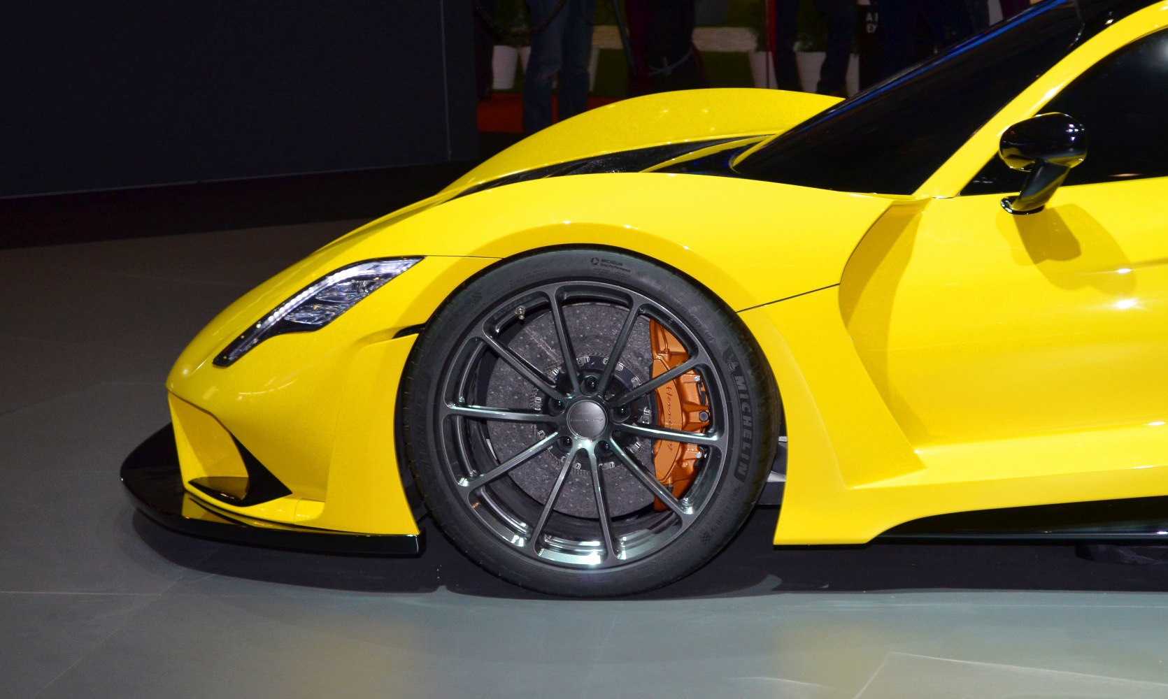 Close-up of yellow supercar front wheel with brake caliper and aerodynamic body