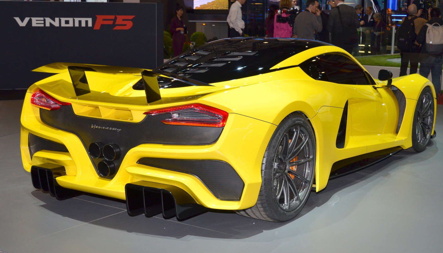 Yellow rear view with quad exhausts, large wing, tail lights, and aerodynamic design