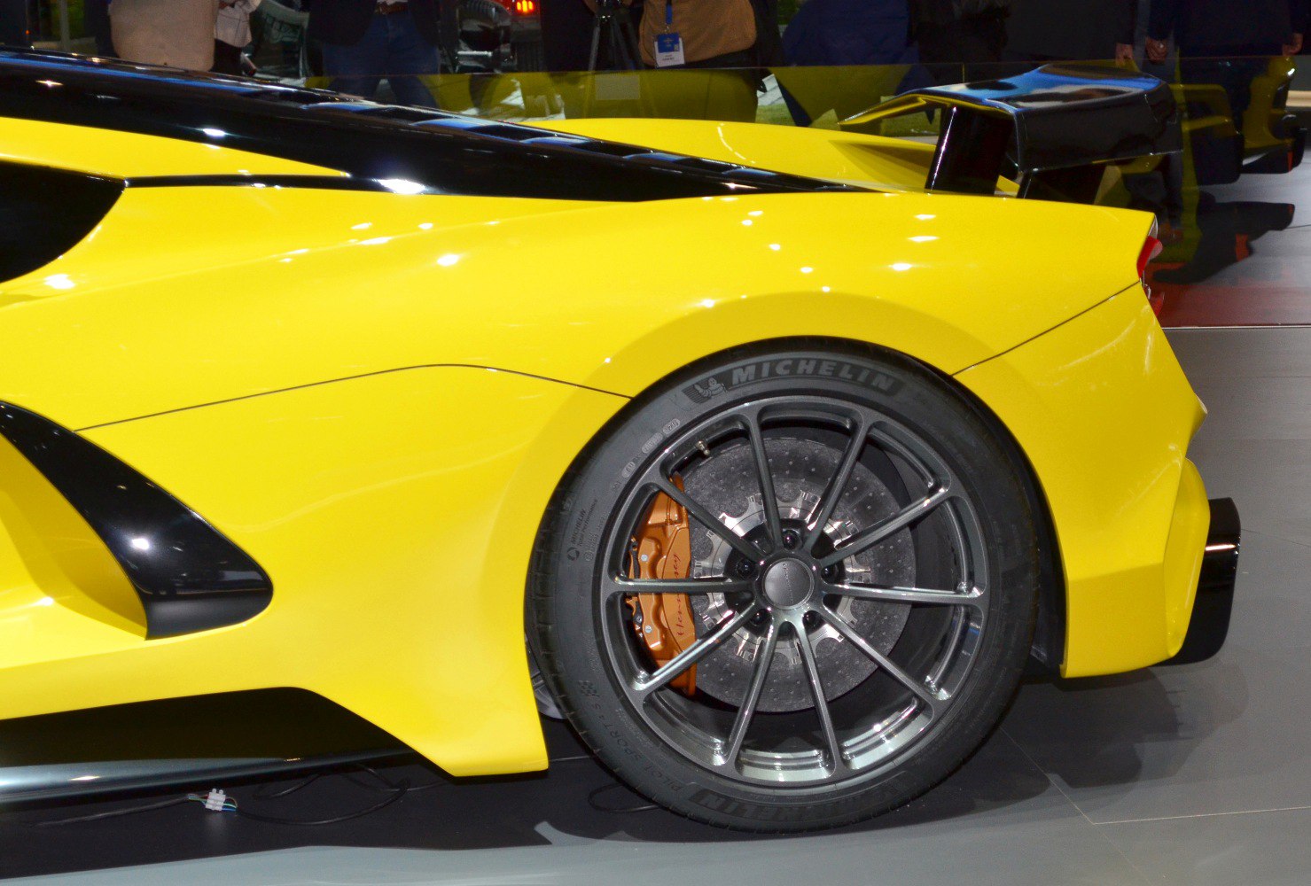 Rear wheel with Michelin tire and large rear spoiler of yellow sports car