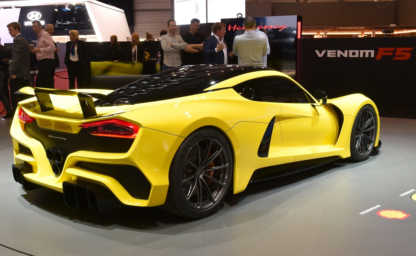 Rear view of yellow sports car with large spoiler and triple exhaust.