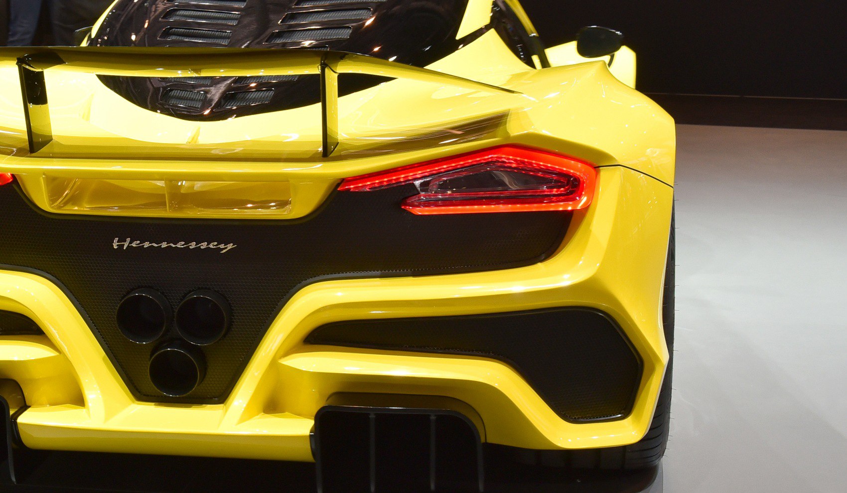 Rear view with triple exhaust pipes, spoiler, and modern tail lights