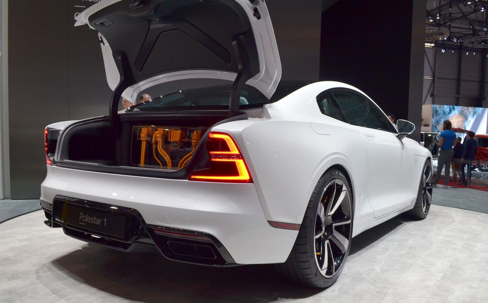 Rear view of car with illuminated tail lights and open trunk showing battery system