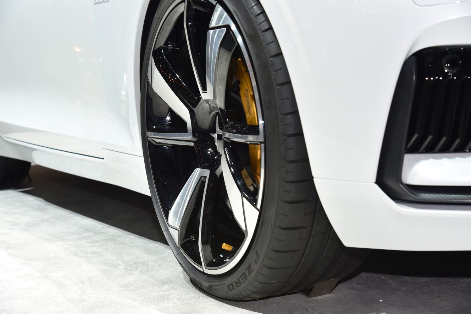 Close-up of alloy wheel and yellow brake caliper on a white car.