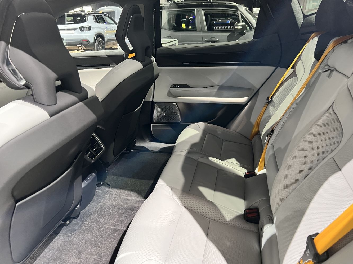 Spacious rear leather seats with yellow seat belts and modern door panel