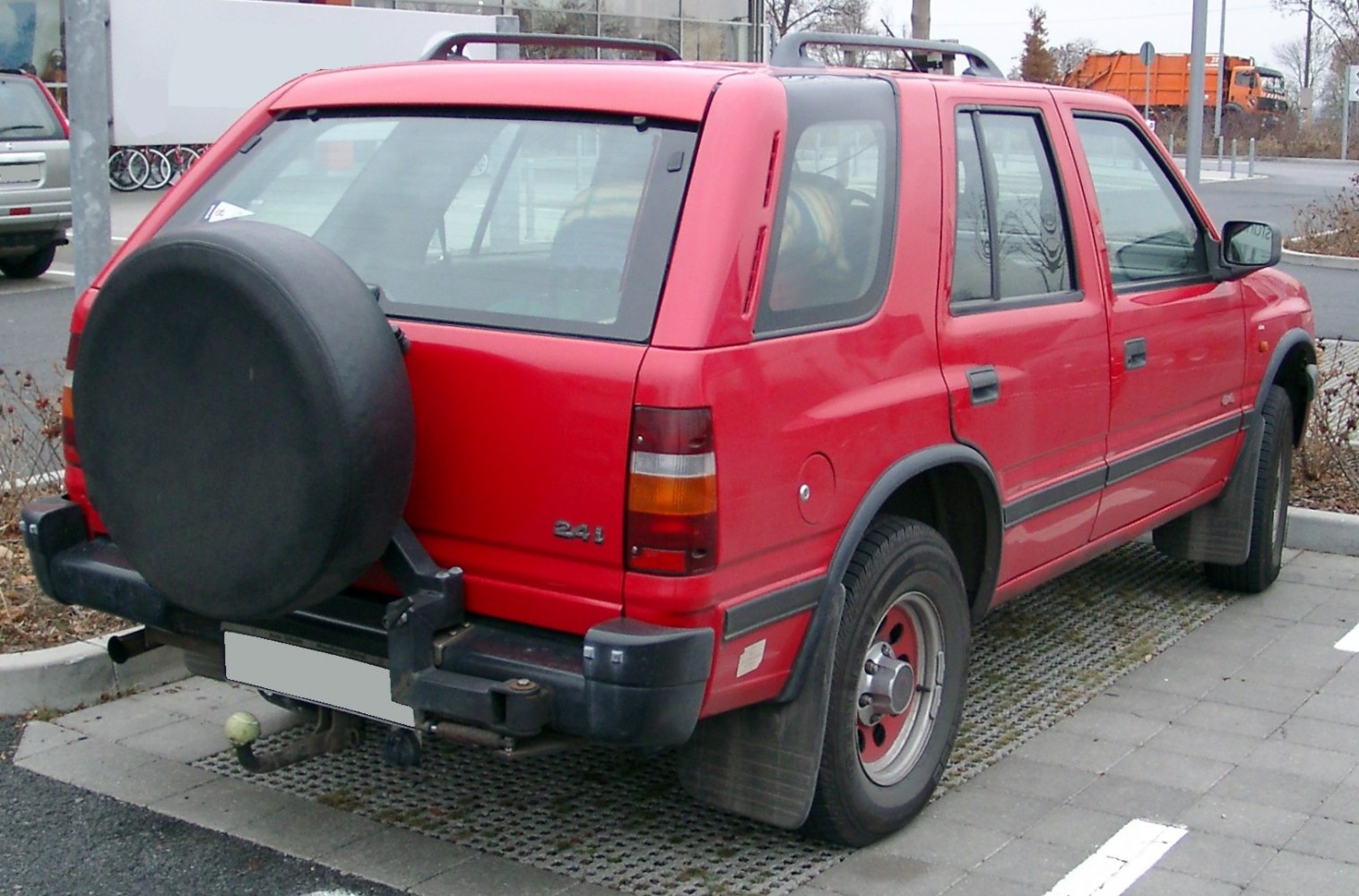 Red SUV with rear spare tire and roof bars