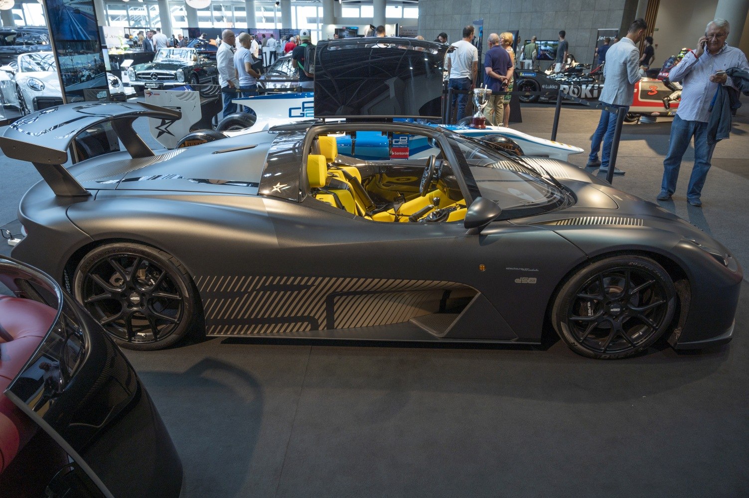 Matte finish sports coupe with yellow bucket seats and carbon fiber rear wing