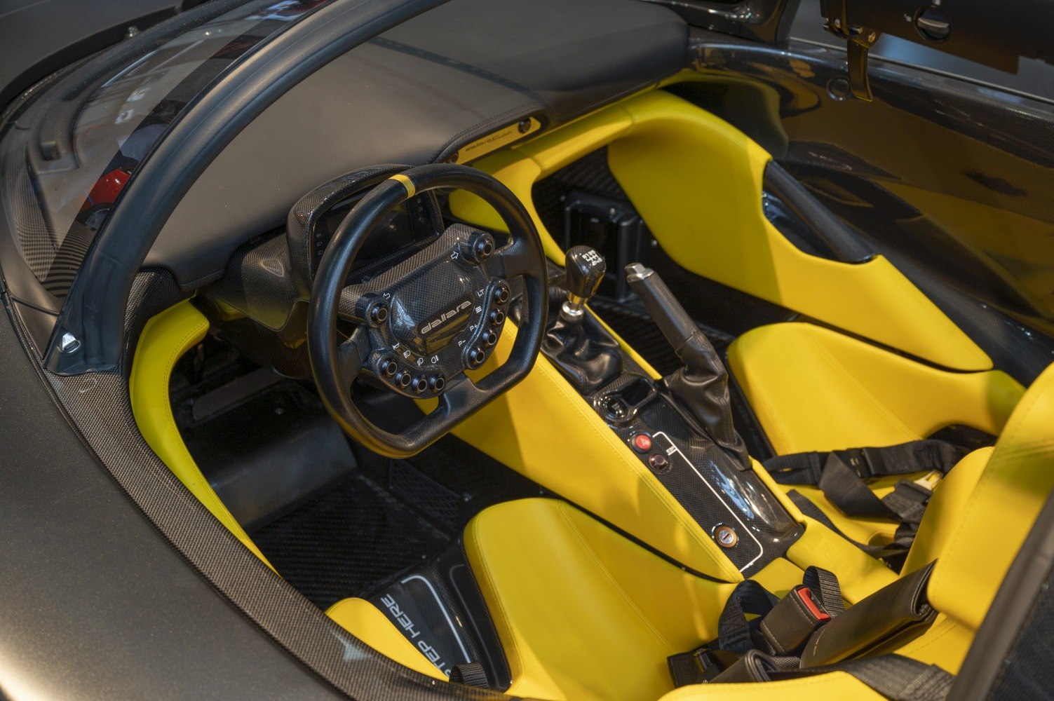 Carbon fiber steering wheel and vibrant yellow racing seats in a sporty car interior
