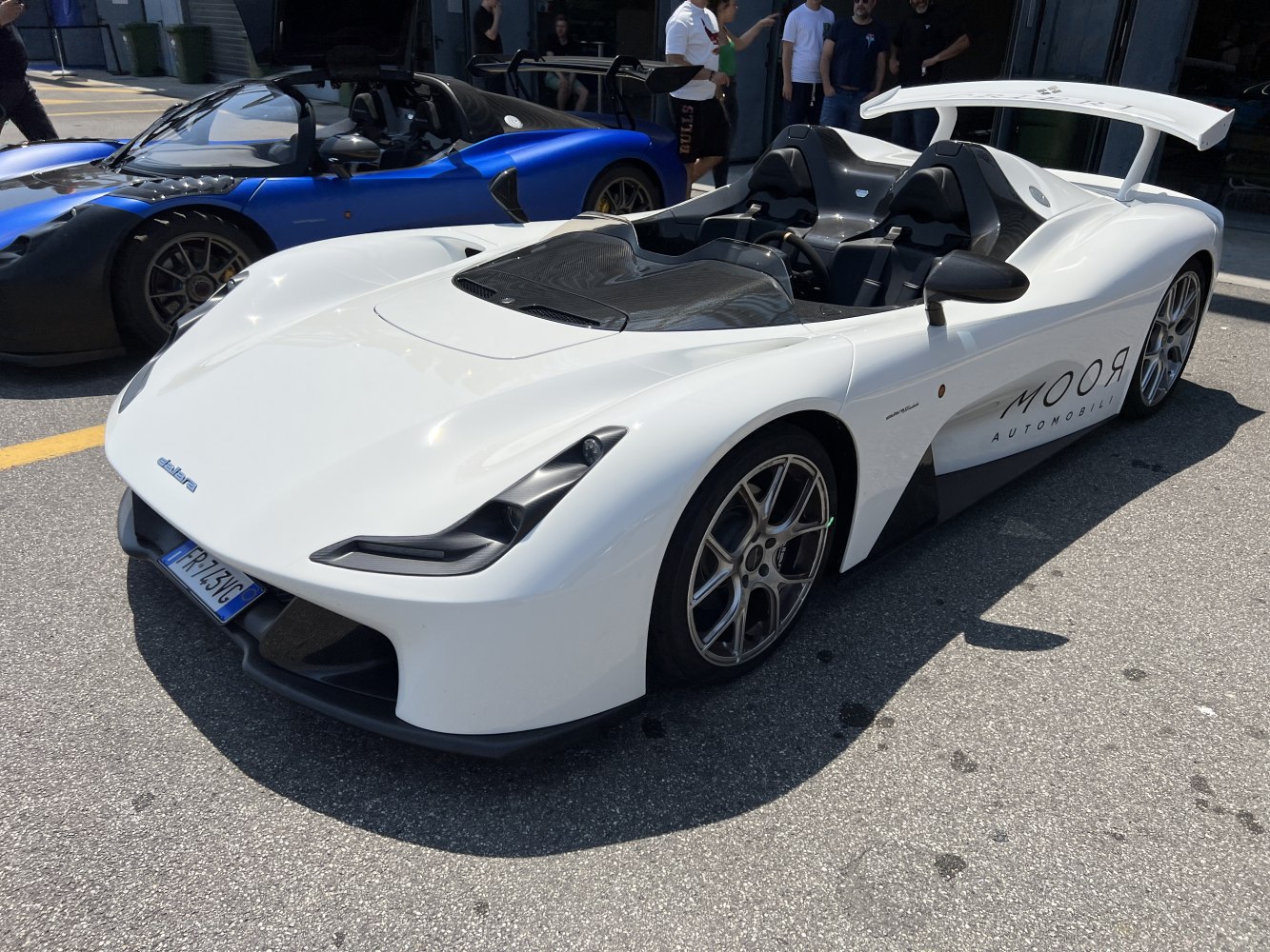Open-top lightweight sports car with aerodynamic rear wing and twin seats