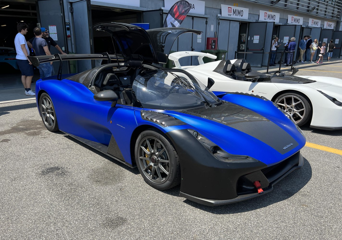 Blue and black aerodynamic sports car with rear wing and gullwing doors