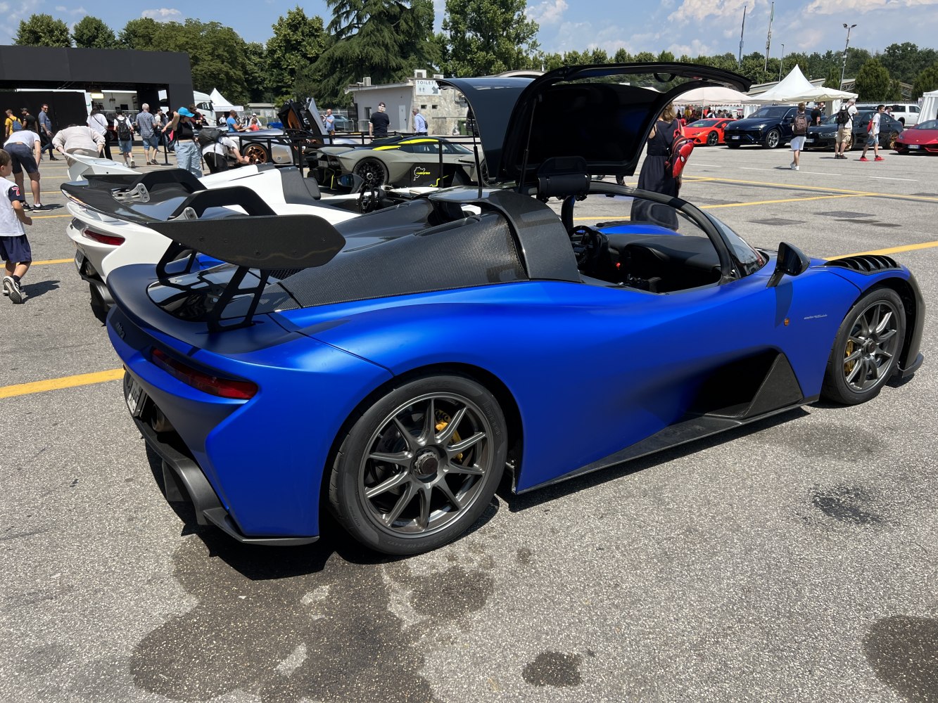 Blue sports car with carbon fiber rear wing and open gullwing door