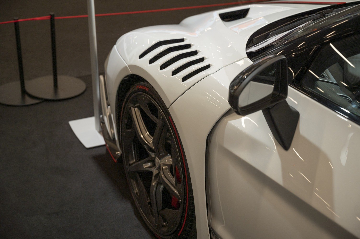 Side air vents and black multi-spoke wheel with red tire stripe.