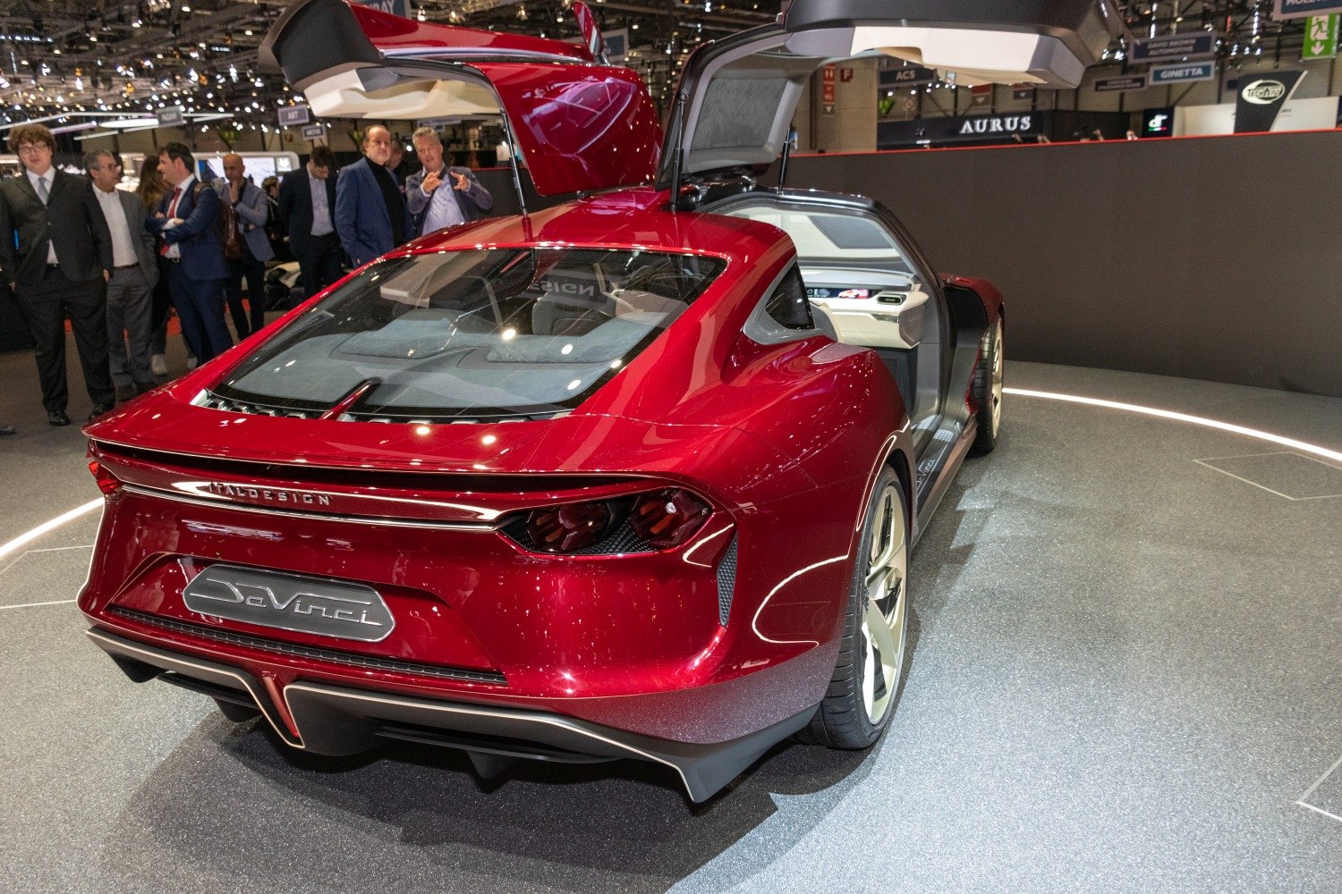 Red concept sports car with gullwing doors and sleek rear design.