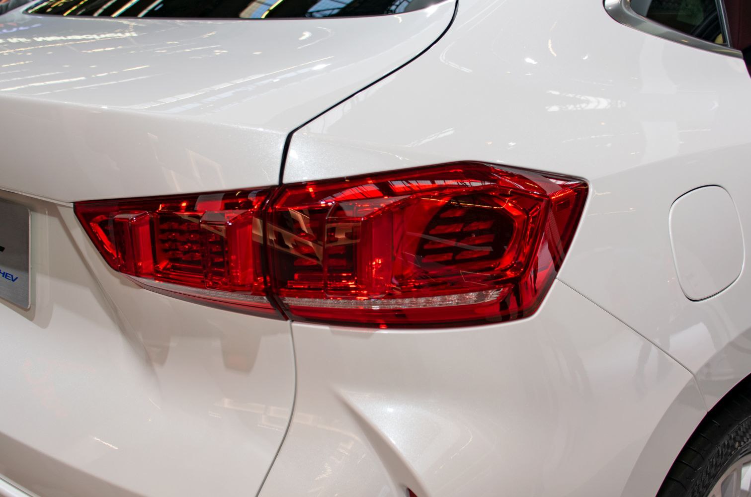 Close-up of rear left LED tail light and white body panel.