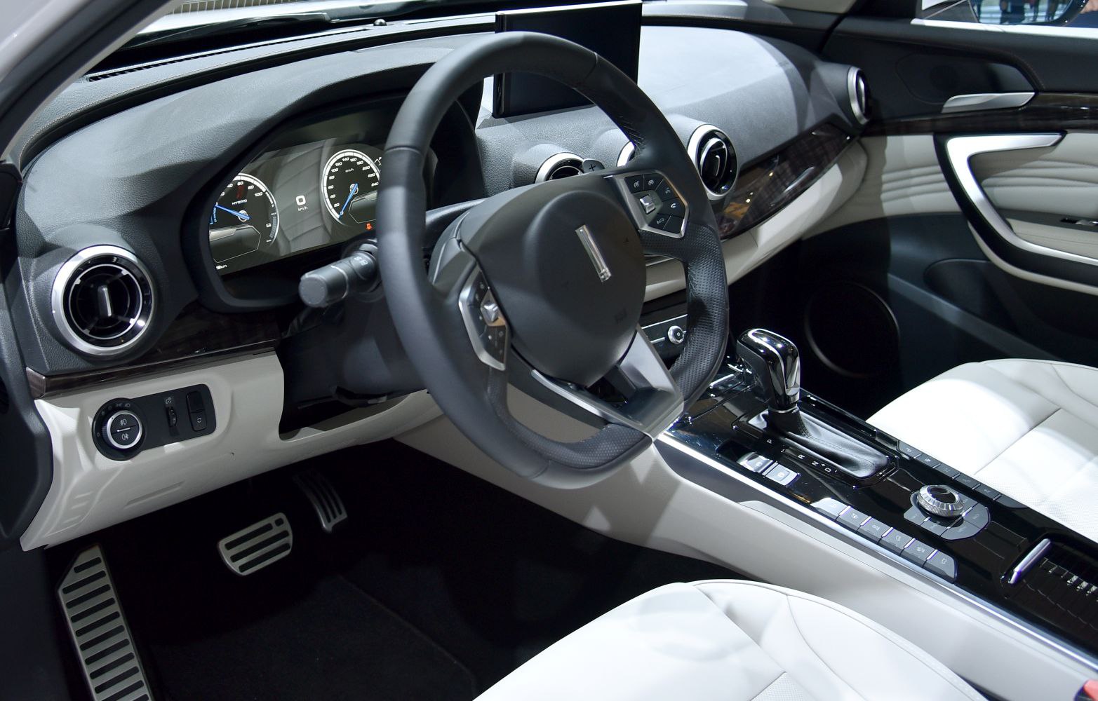 Dashboard, steering wheel, center console, gear shift, and pedals of a modern car interior.