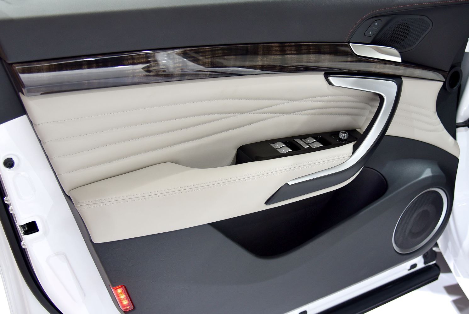 Luxury car door panel with controls and speaker.