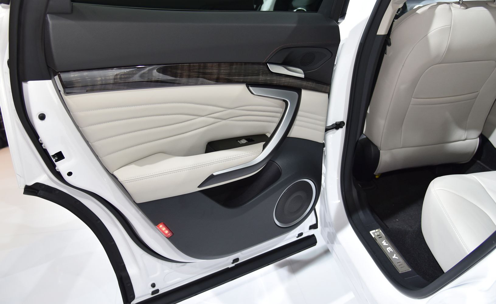 Luxury car door panel with beige leather, wood trim, and metallic accents