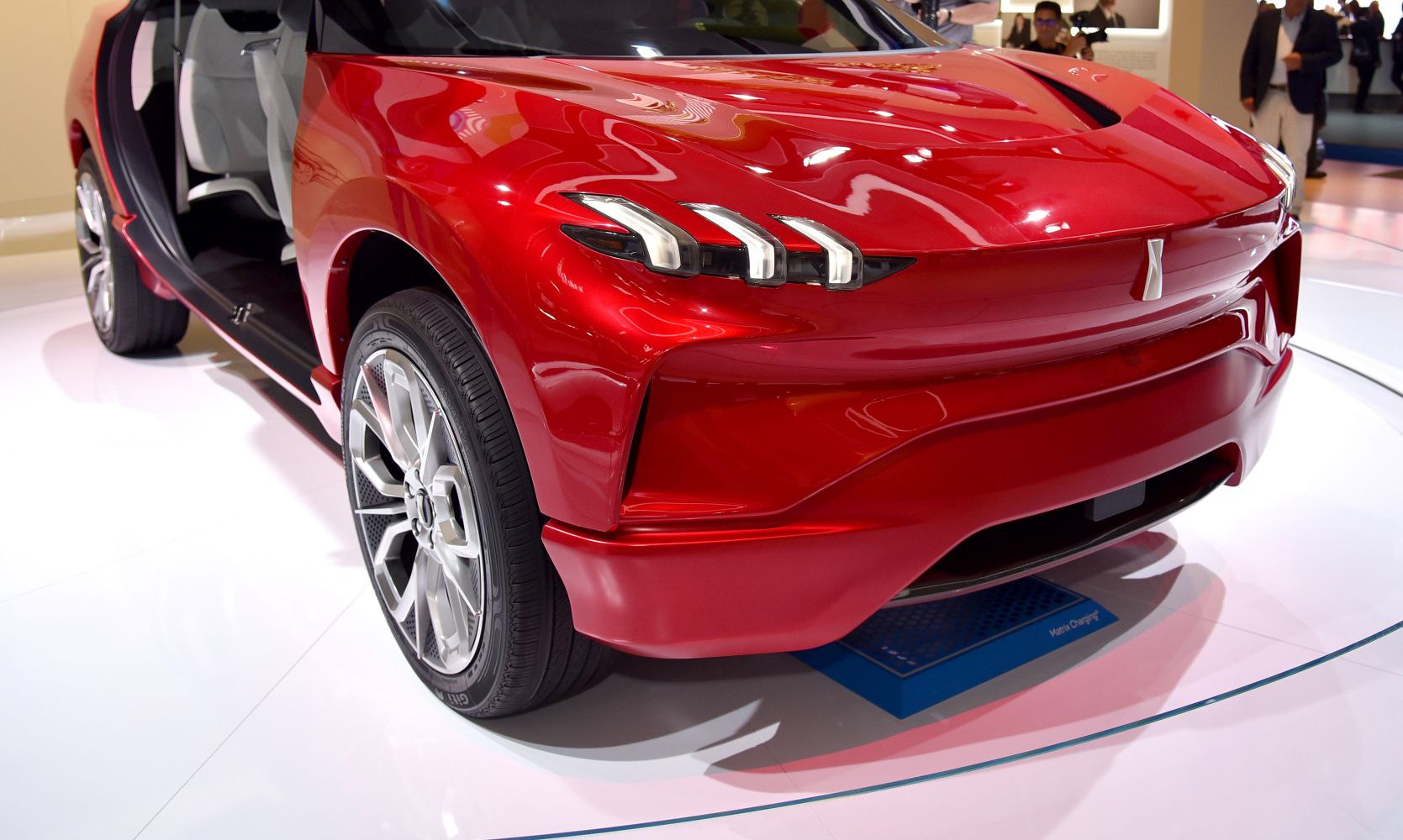 Triple LED headlights and futuristic aerodynamic front design of a red concept SUV.