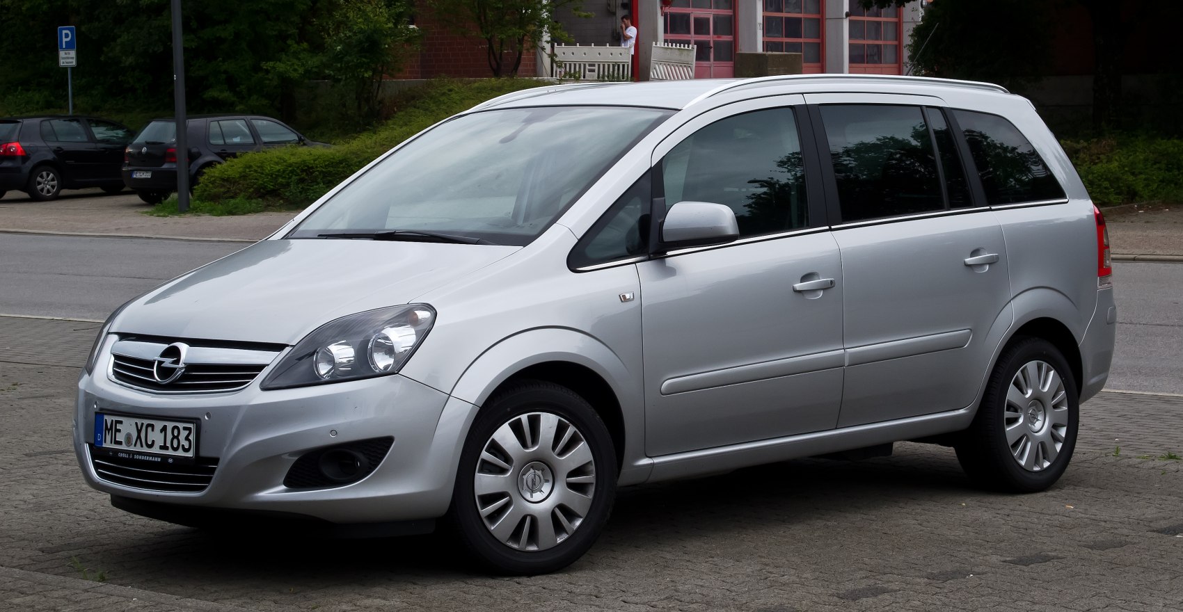 Silver minivan with distinct headlights and hubcaps, front side view