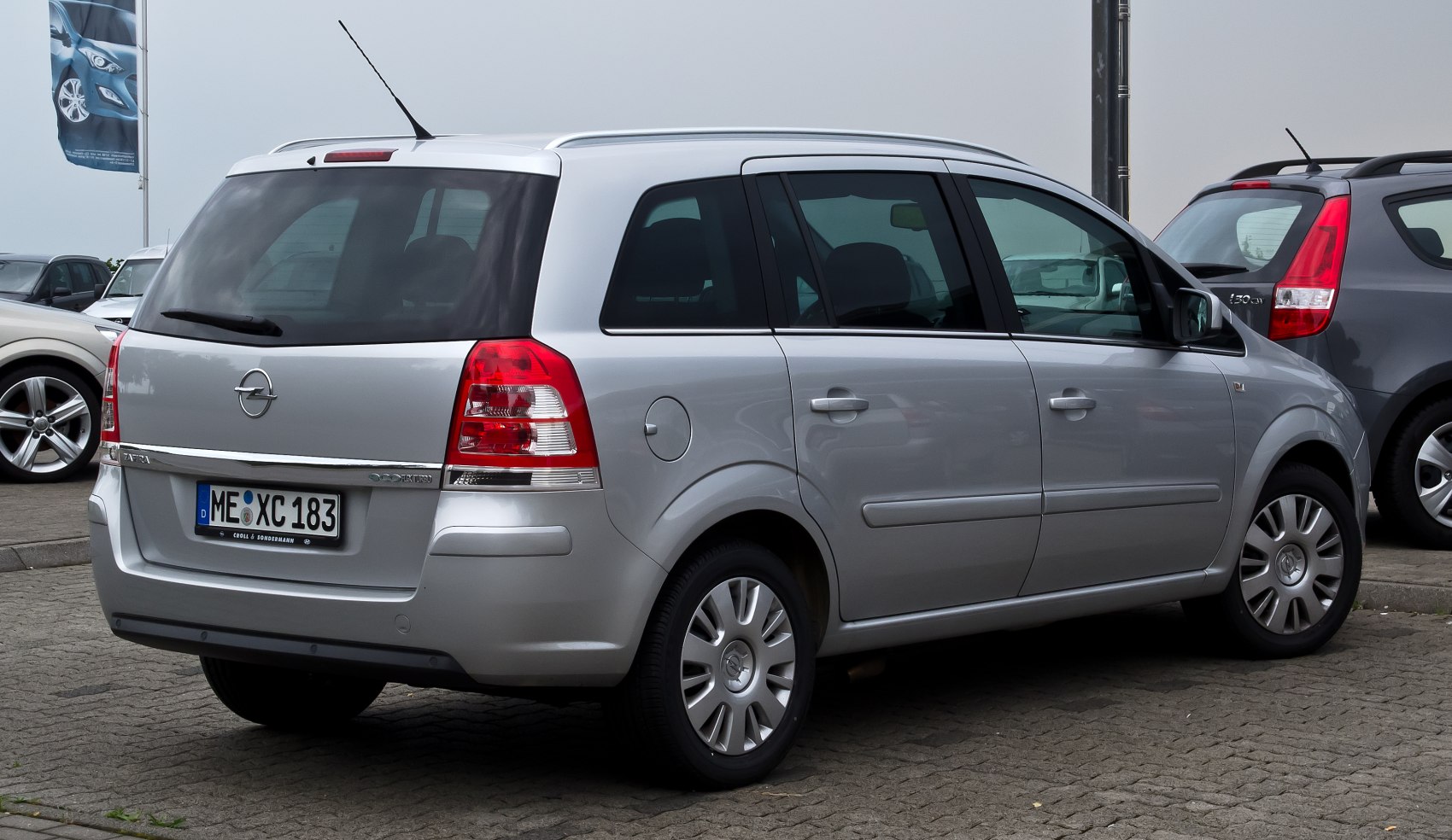 Rear and side profile of silver MPV with roof rails and clear taillights